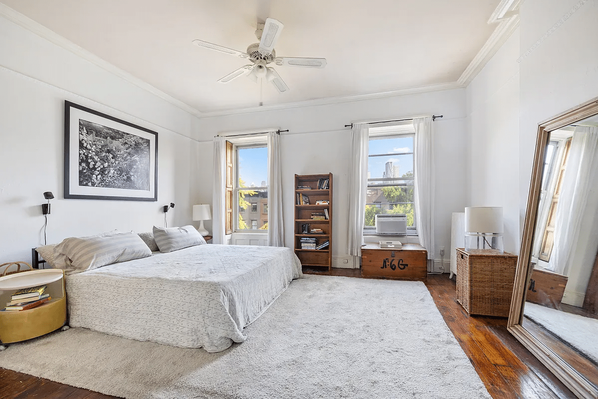 Bedroom with ceiling fan, picture ledges, two windows