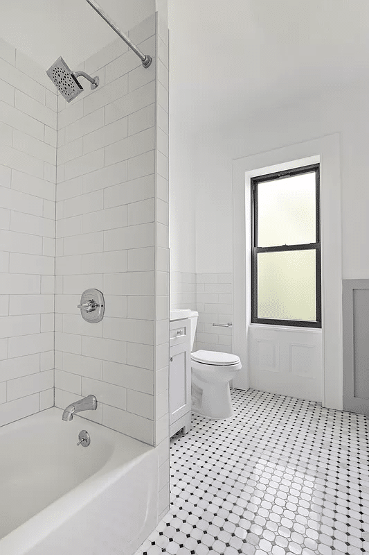 bathroom with white fixtures, wall tile and black and white floor tile