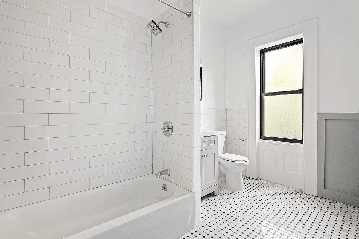 bathroom with white fixtures, wall tile and black and white floor tile