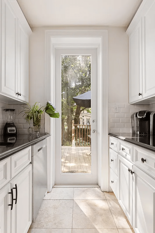 Kitchen with white cabinets, glass door to the terrace