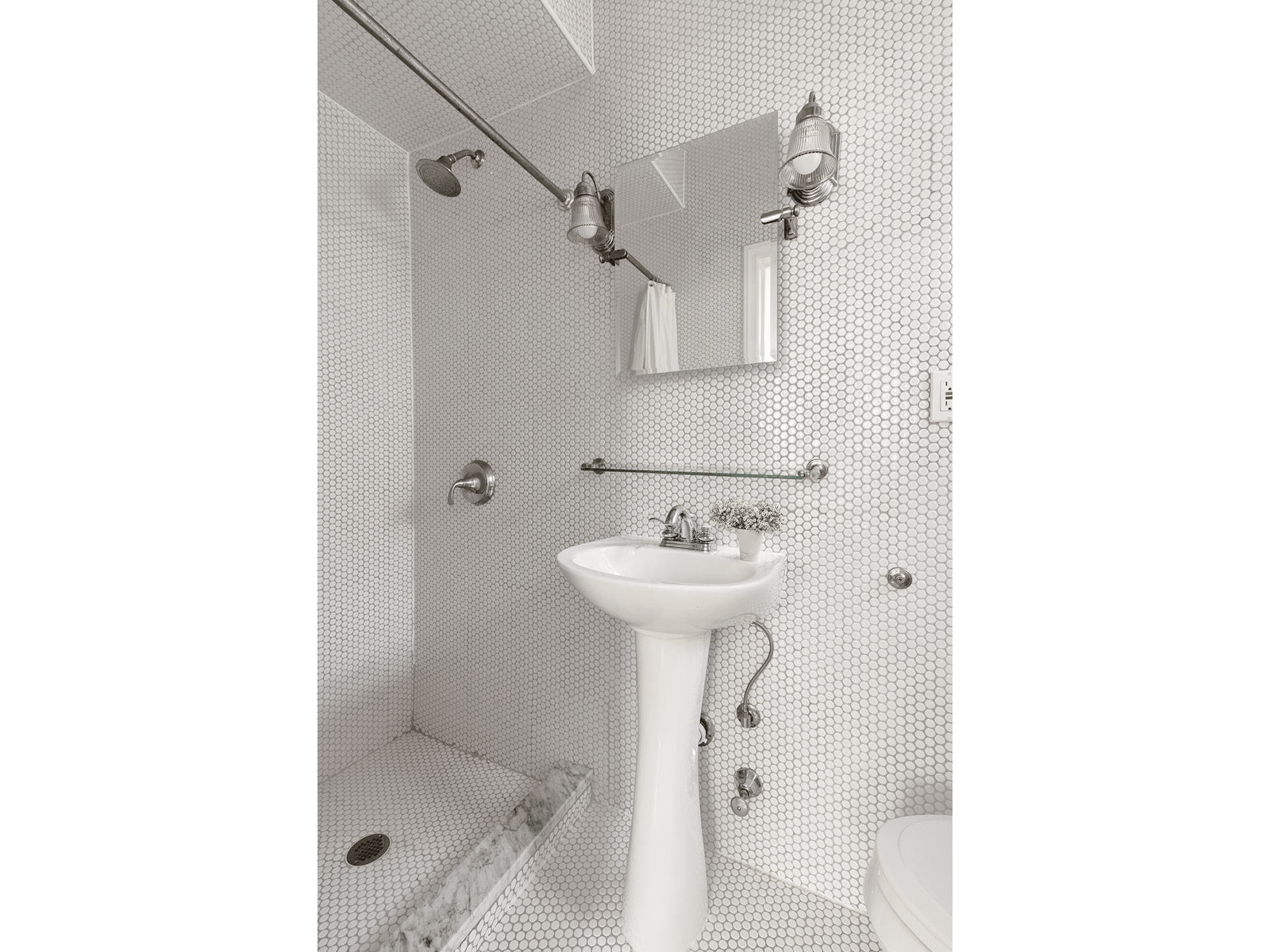 Bathroom with white penny tiles on walls and floor and an open shower