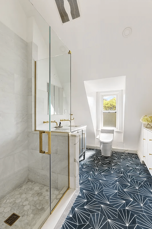 Bathroom with graphic floor tiles, shower with glass doors and a double vanity