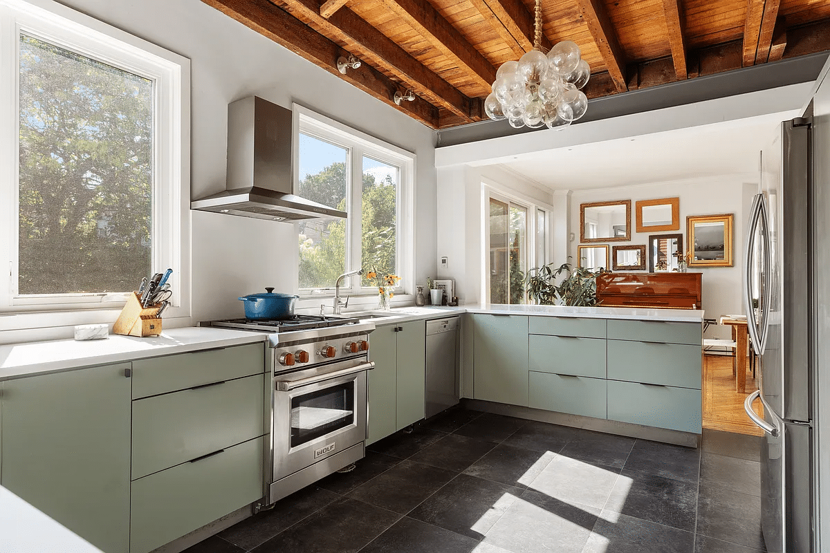 Kitchen with exposed beams, green base units and dark tiled floor