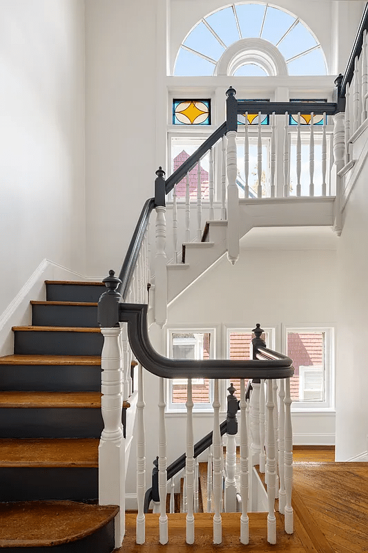 Staircase with white painted balusters and dark railing