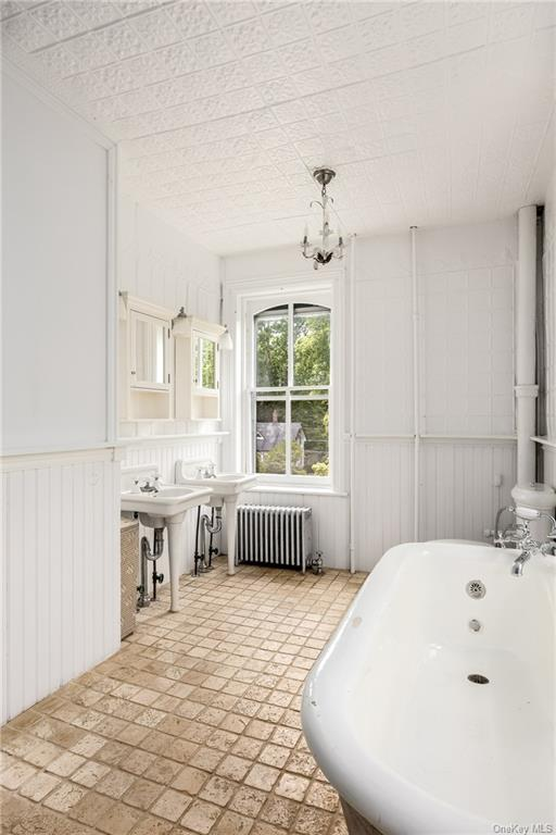 bathroom with two pedestal sinks, tin ceiling