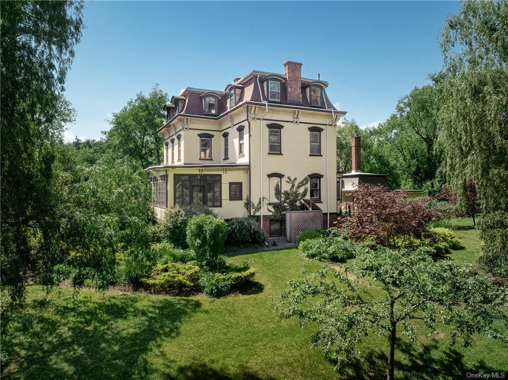 view of rear of mansard roofed house with sun porch