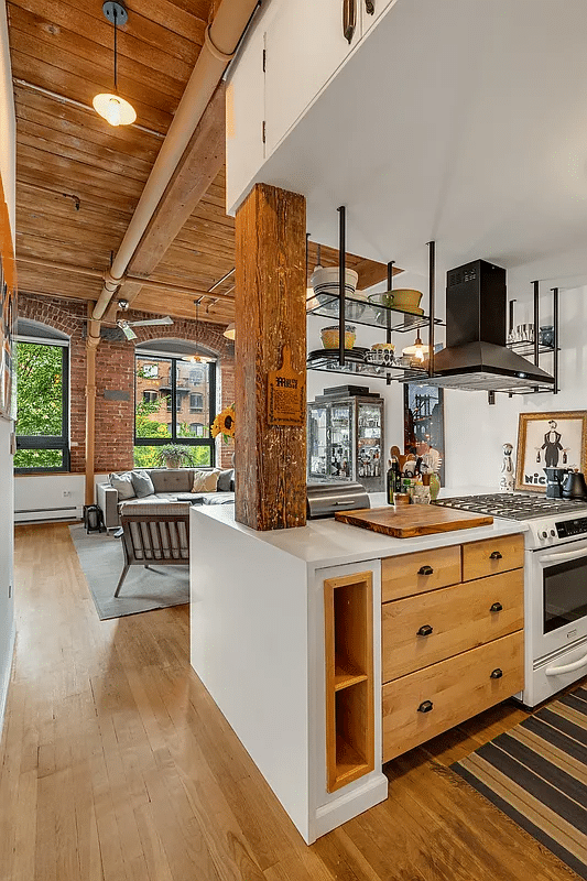 view from kitchen to living room with exposed beams, pipes and bricks