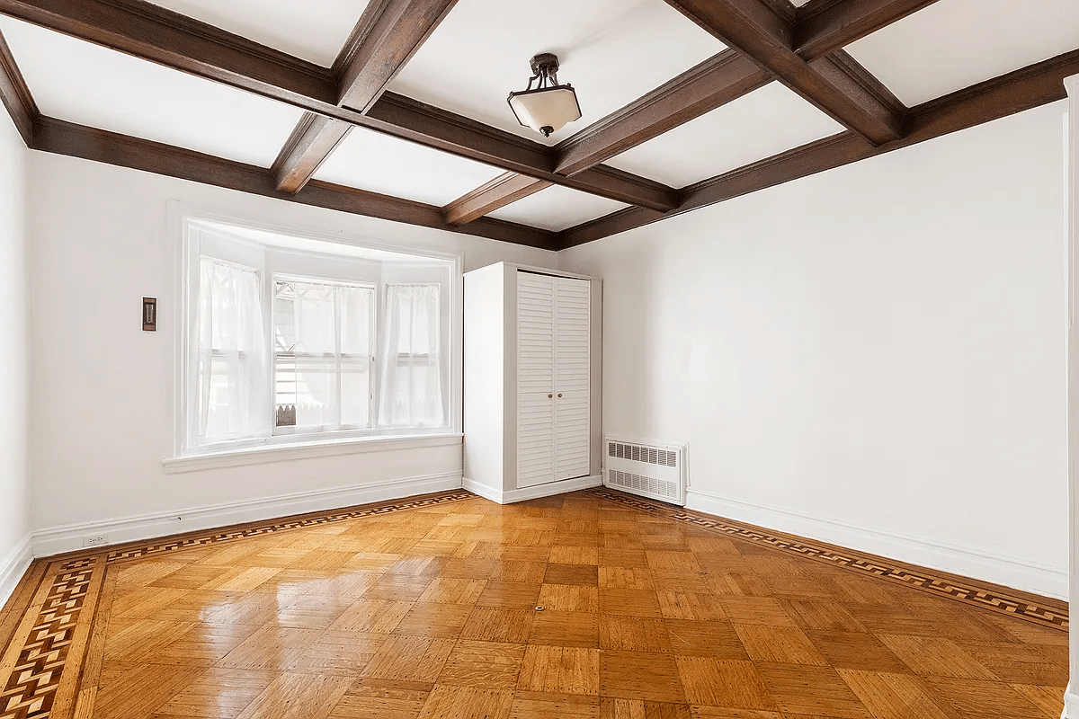 former dining room turned bedroom with wood floor, coffered ceiling