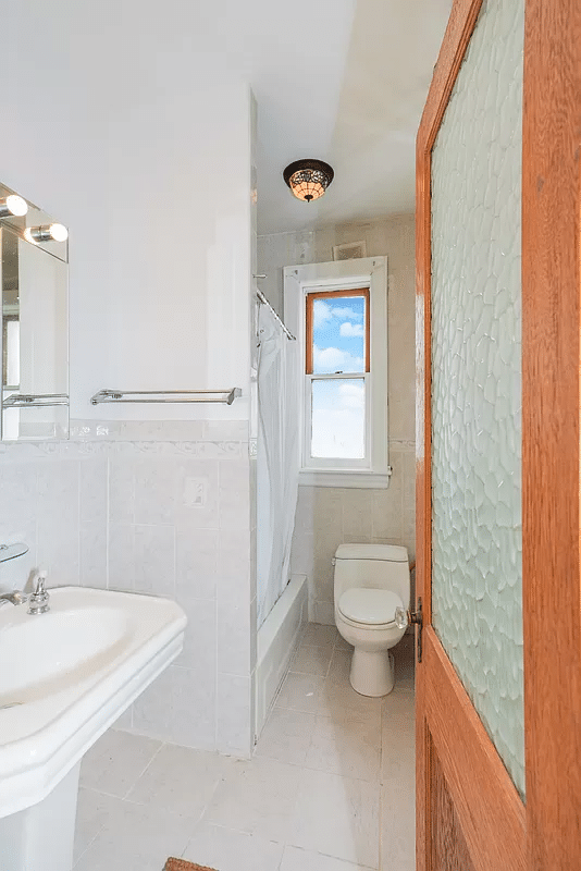 bathroom with opaque, textured glass door, white fixtures