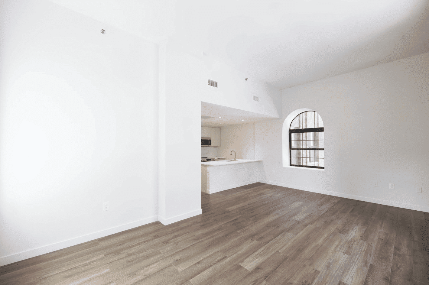 living room with arched window and view into kitchen with white cabinets and counter