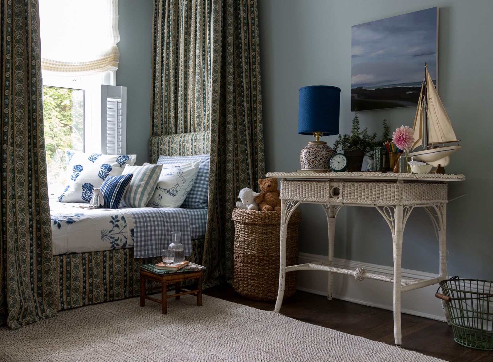 bedroom with canopied bed, blue walls and a wicker table