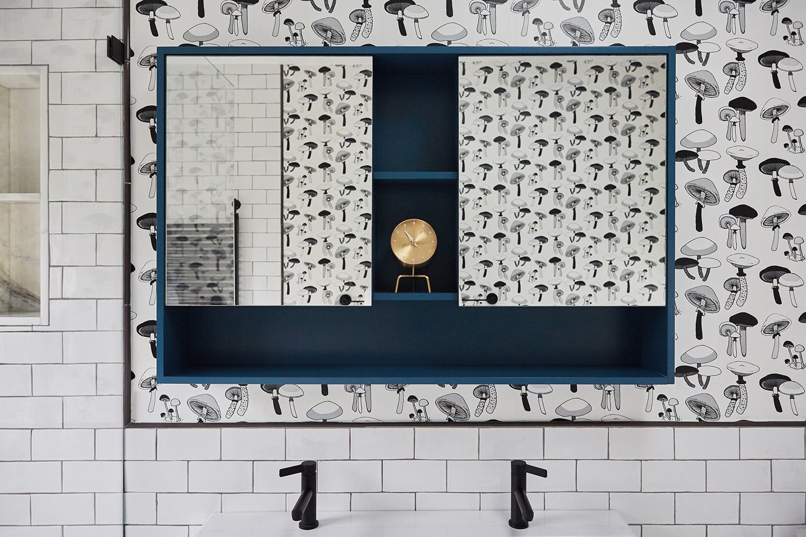 One of several baths in the family’s triplex is distinguished by a panel of charming mushroom wallpaper from Hartland Brooklyn, inset into a field of white subway tile