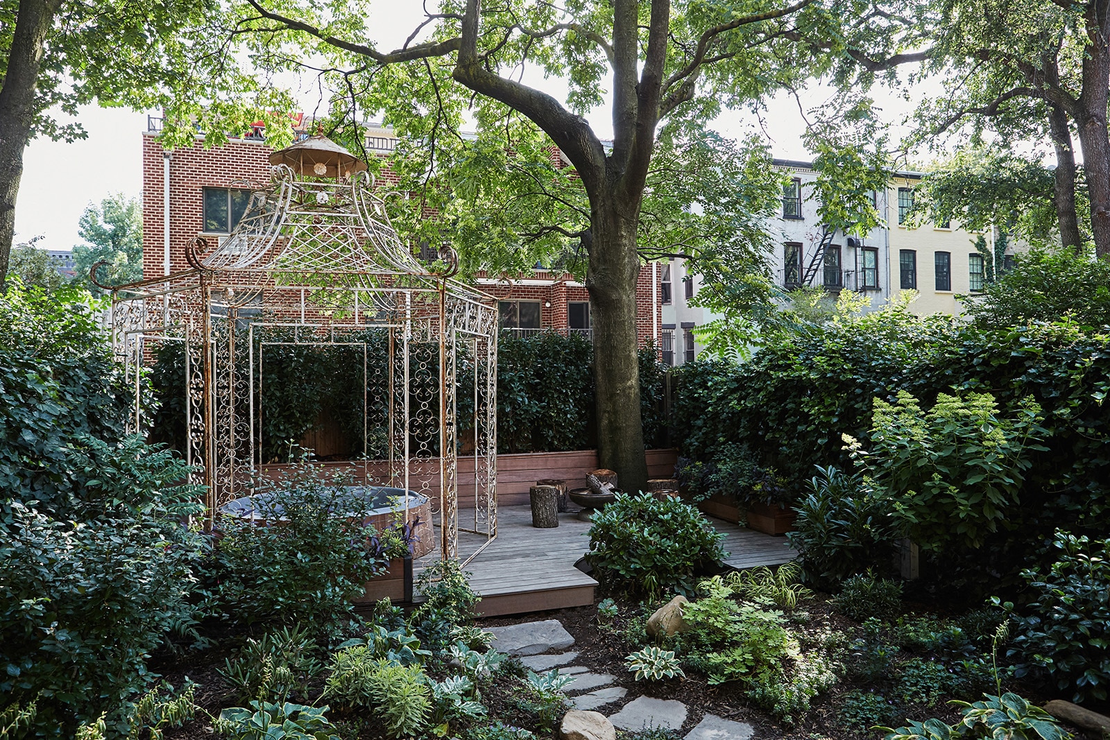 A much-used hot tub sits beneath an antique iron gazebo purchased from The Old Grainery, an architectural salvage depot in Payson, Illinois. The tidy landscaping, a palette of varied greens, is the work of Brooklyn-based Urbangreen Gardens