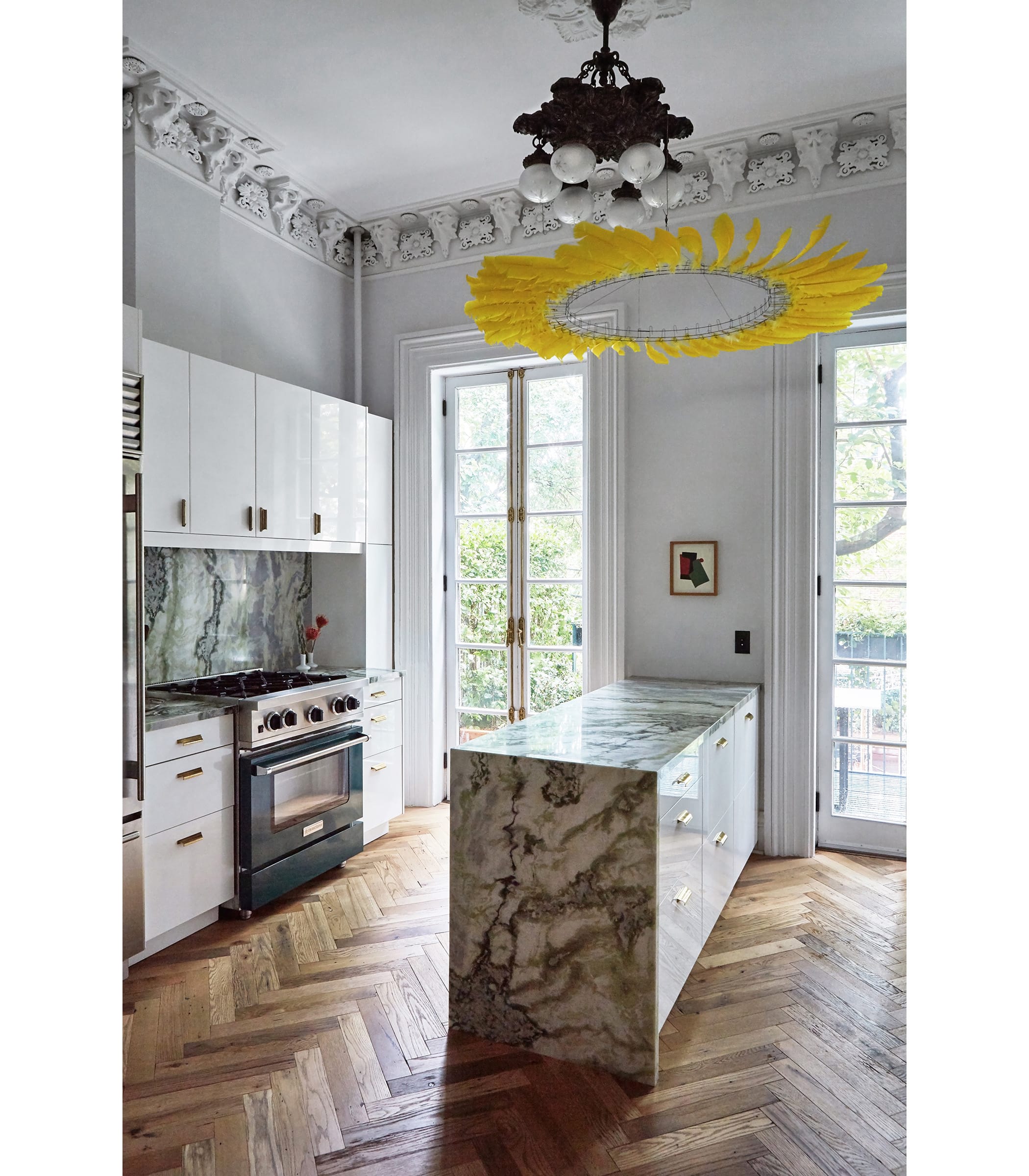 Galli took a high-low approach to the kitchen at the rear of the parlor floor, upgrading glossy white cabinetry from Ikea with countertops and a backsplash of polished River Jade marble, a Sub-Zero fridge, and a range from BlueStar. A ring of yellow feathers by kinetic sculptor Tim Prentice is a quirky touch, suspended from a fixture Galli believes is original to the house