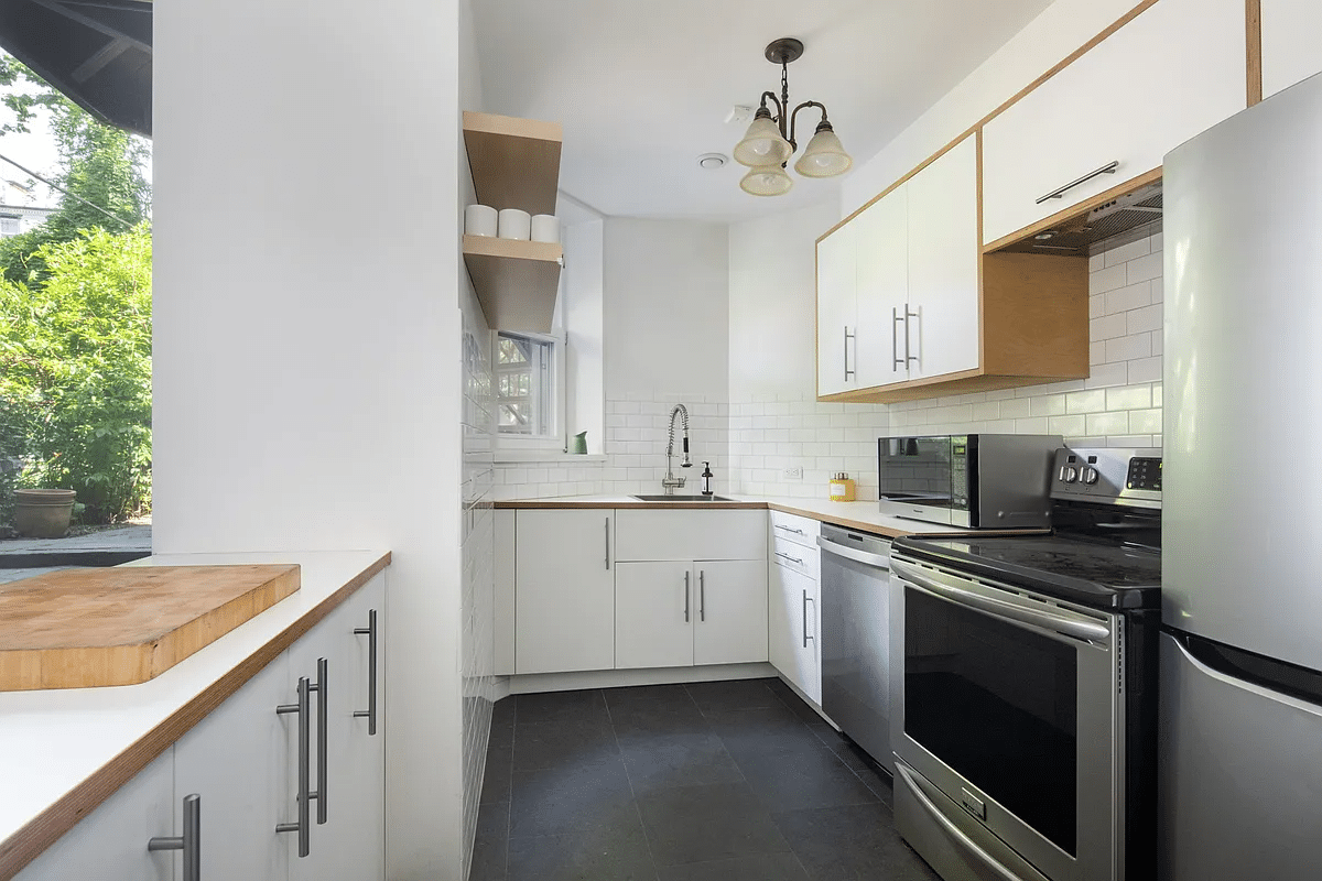 garden level kitchen with white subway tile and cabinets, stainless steel appliances