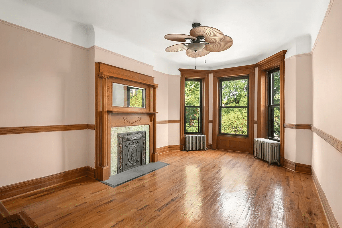 bedroom with mantel, ceiling fan, wood floor