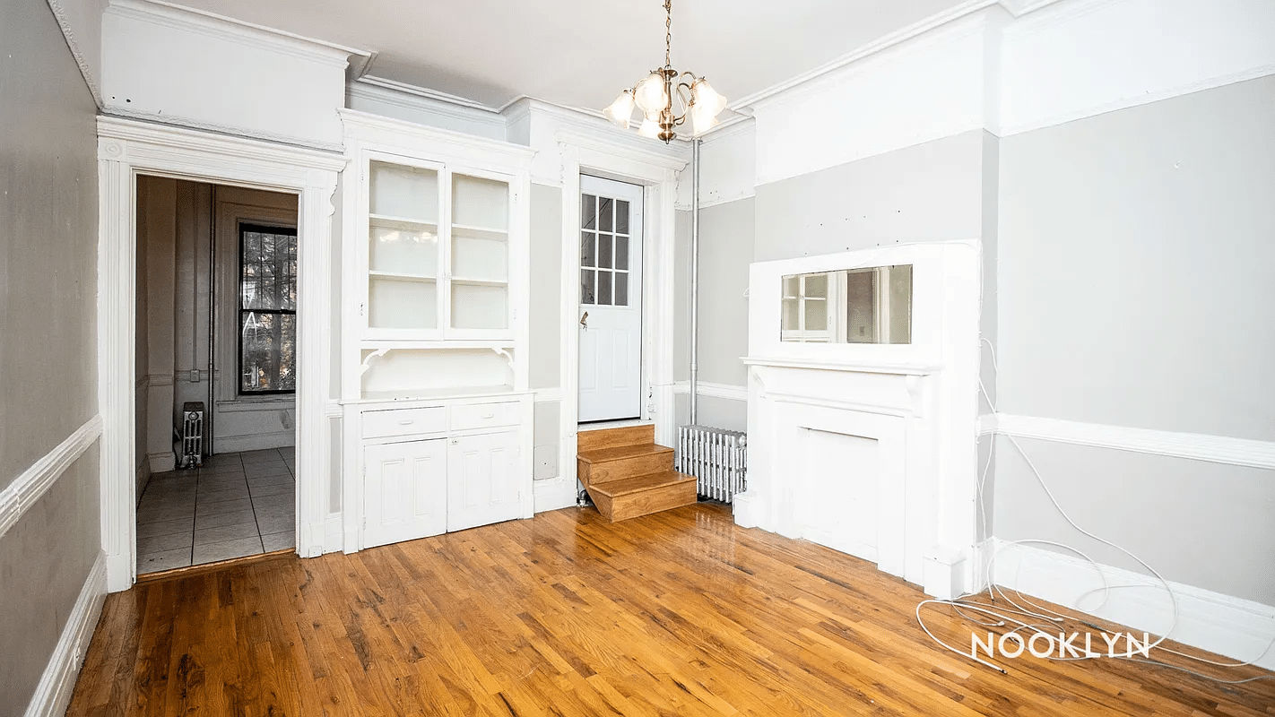 dining room with built-in china cabinet, mantel and steps up to another room