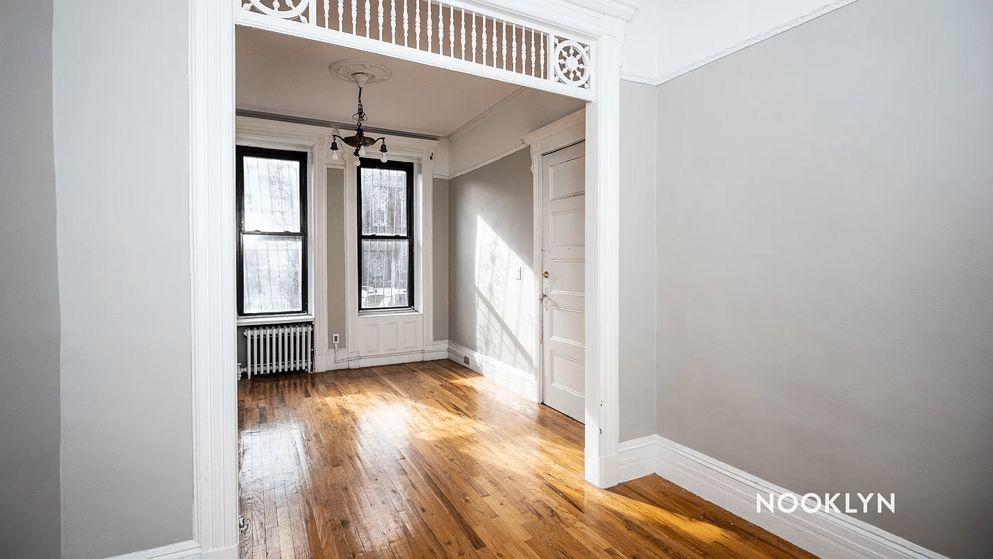 looking through a doorway with fretwork into a room with picture rails, a chandelier