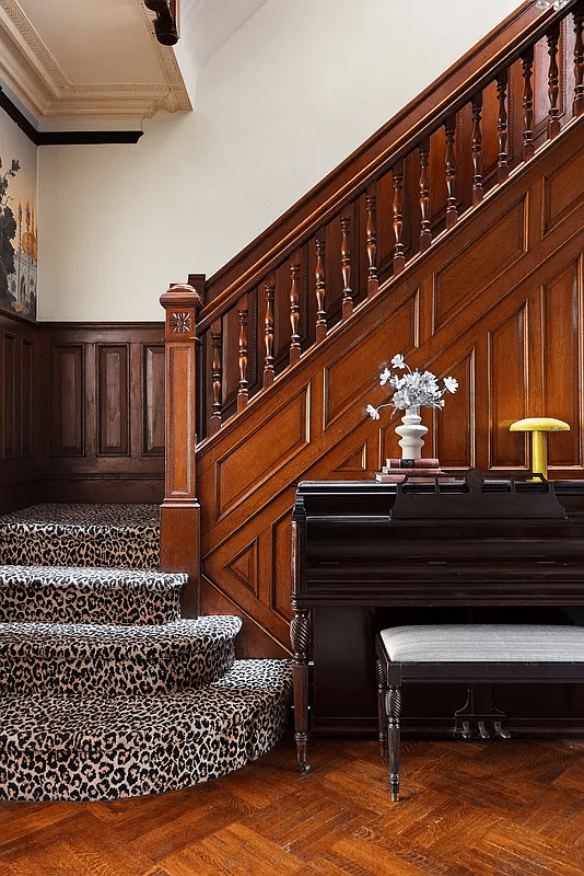 stair with wainscoting and an animal print carpet