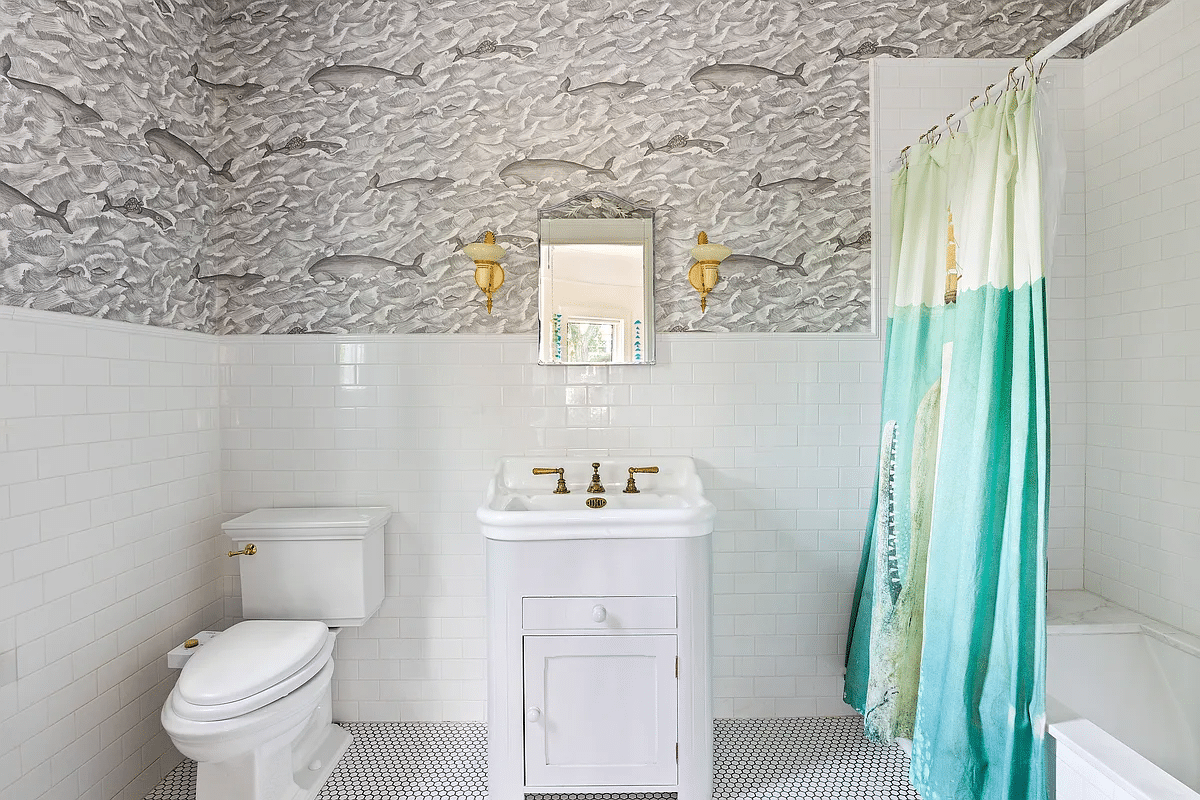 bathroom with white tile and fixtures and wallpaper with whales