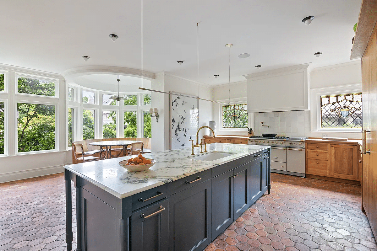 kitchen with large marble topped island, terra cotta tile floor and view to breakfast nook