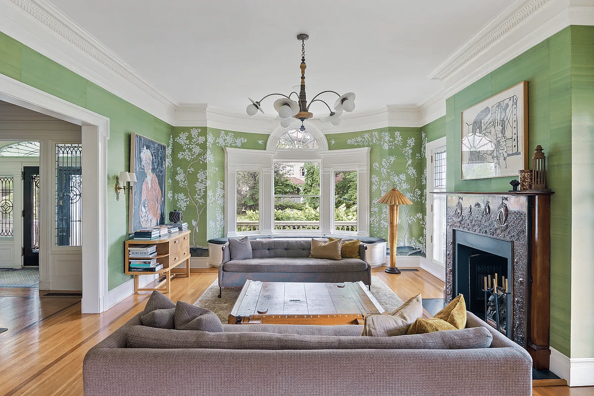 parlor with green wallpaper, a mantel and wood floor