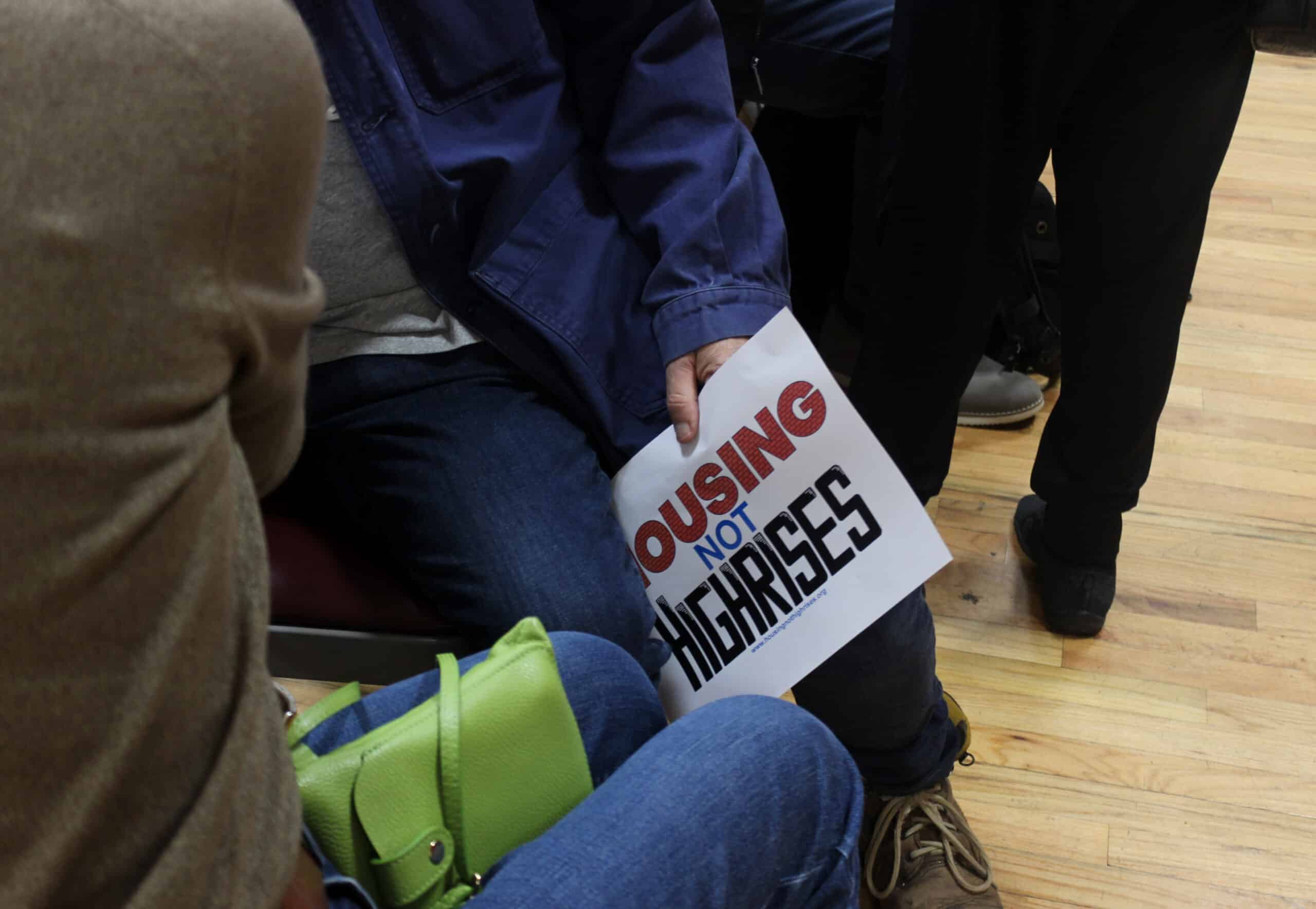 person holding a houses not highrises sign