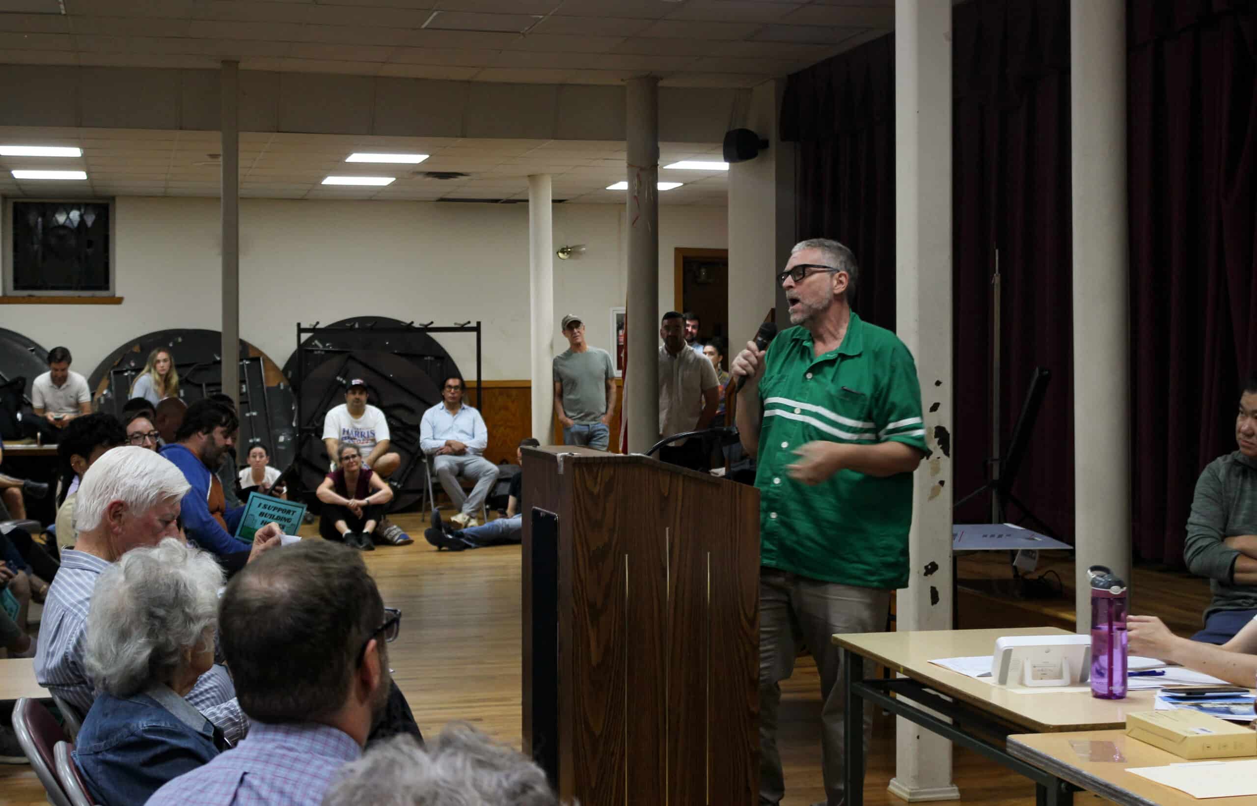 person in a green shirt speaking at a podium