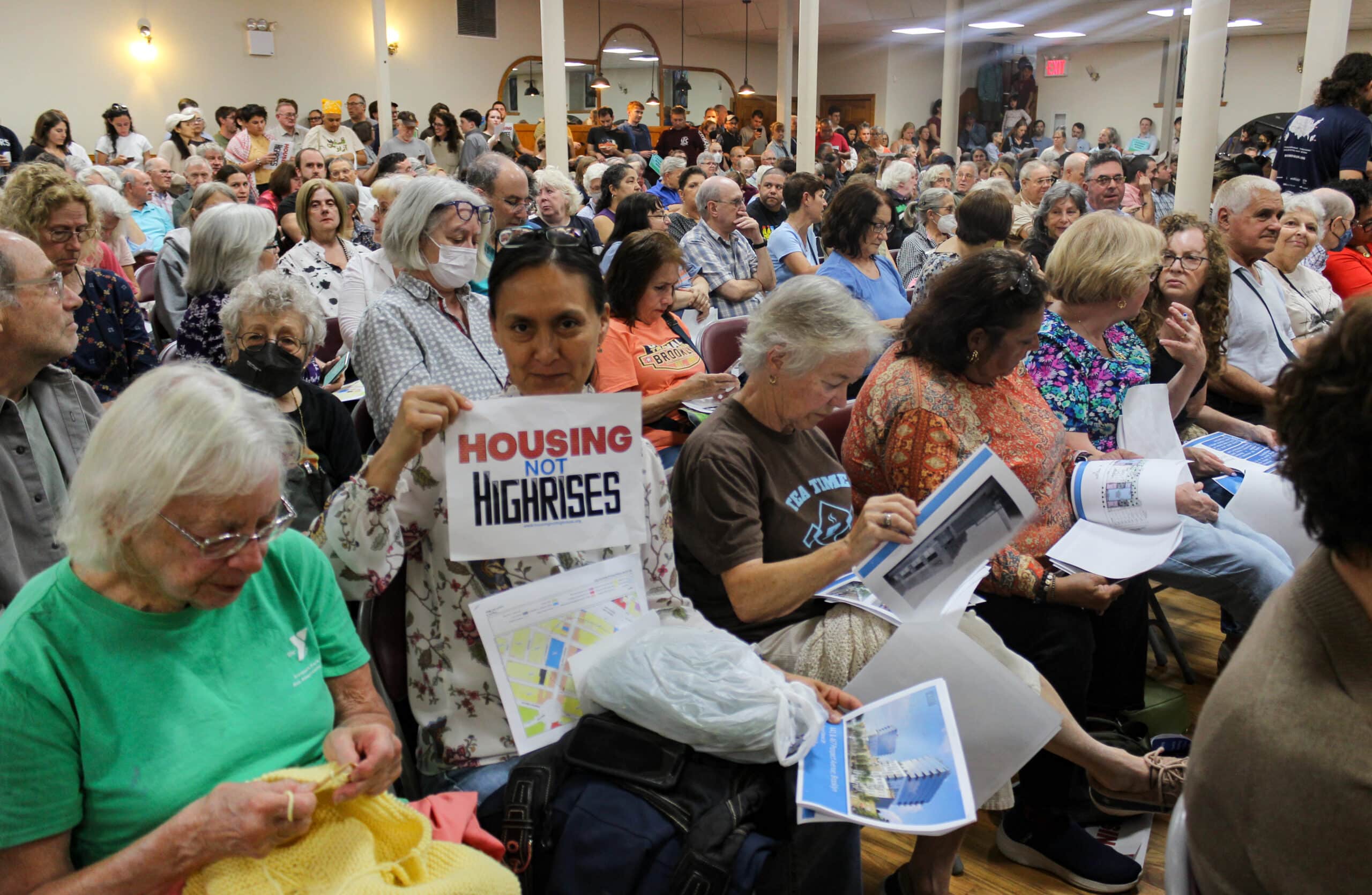 person holding a housing not highrises sign