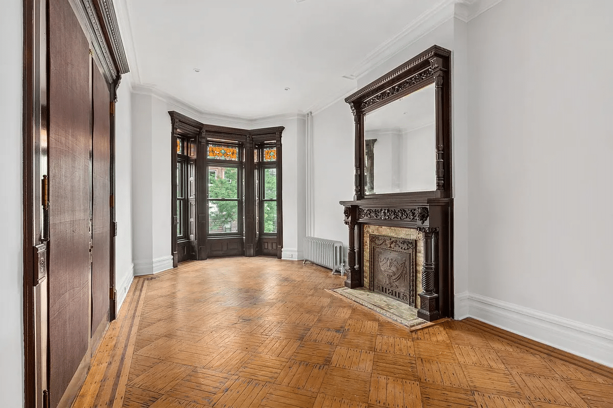 bedroom with mantel, wood floor, bay window