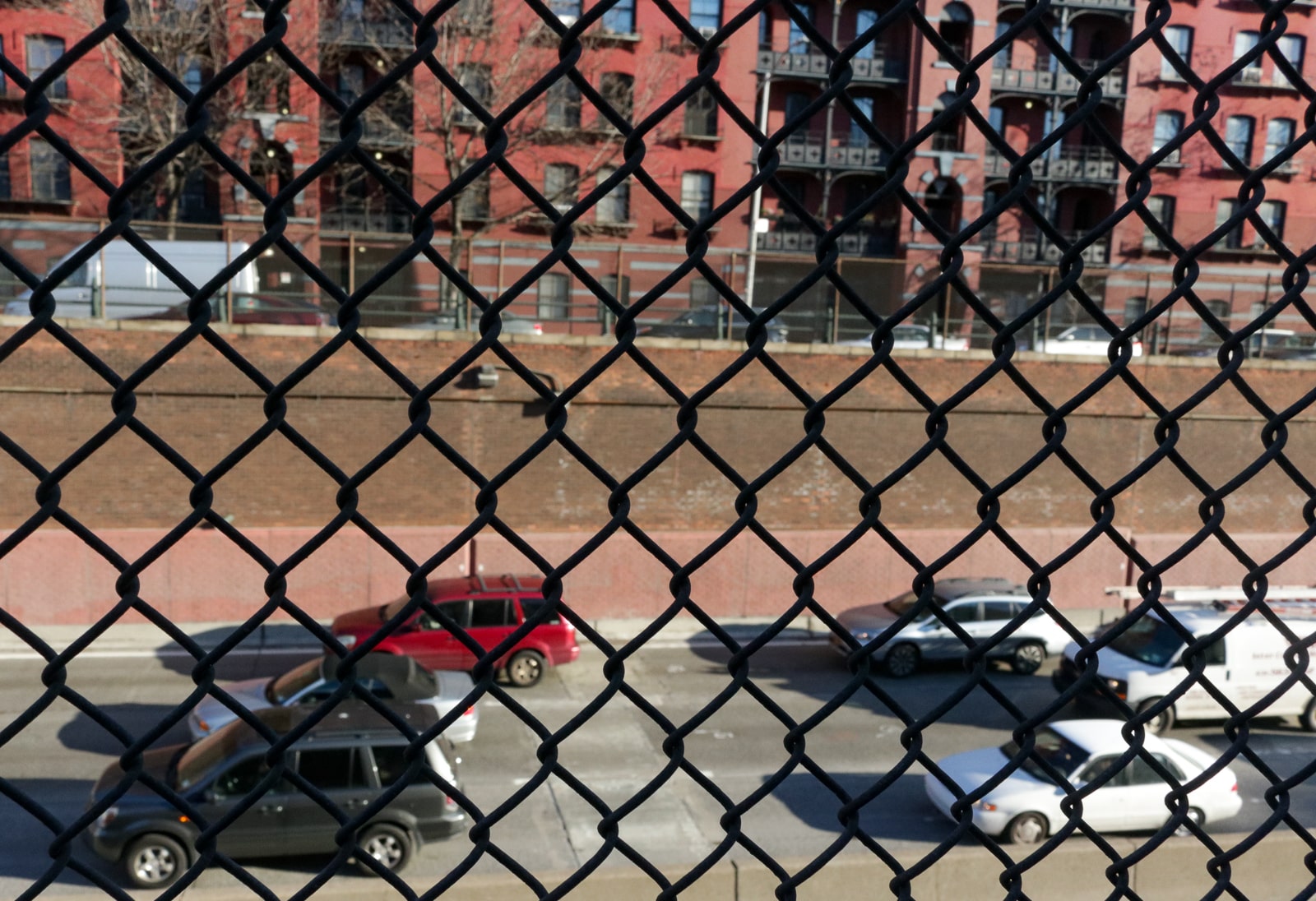 view through a chain link fence to cars below