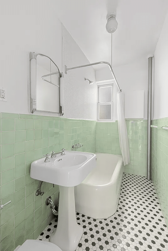 bathroom with green wall tile, vintage white tub and pedestal sink