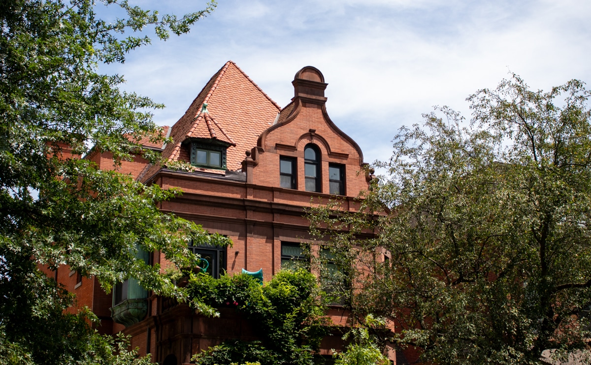 clinton hill - roofline of a red brick mansion amdist the trees on Clinton Avenue