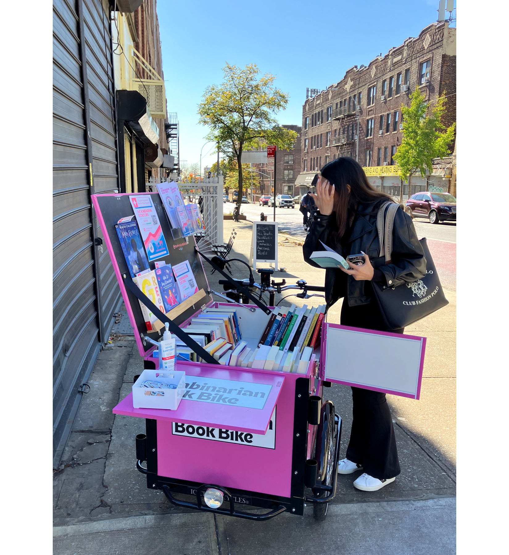 A customer browses the Nonbinarian Book Bike outside the new store