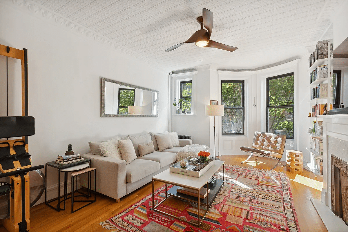 parlor with ceiling fan, tin ceiling and a mantel