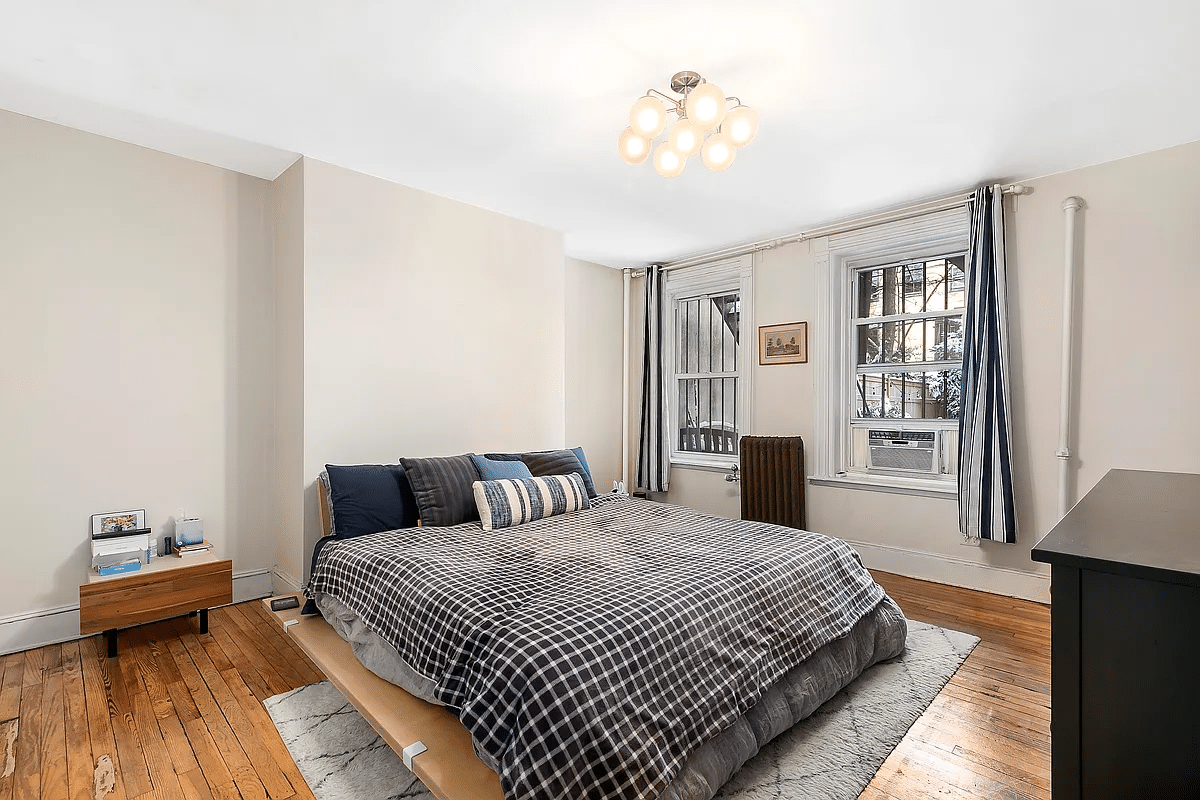 apartment bedroom with wood floor, two windows