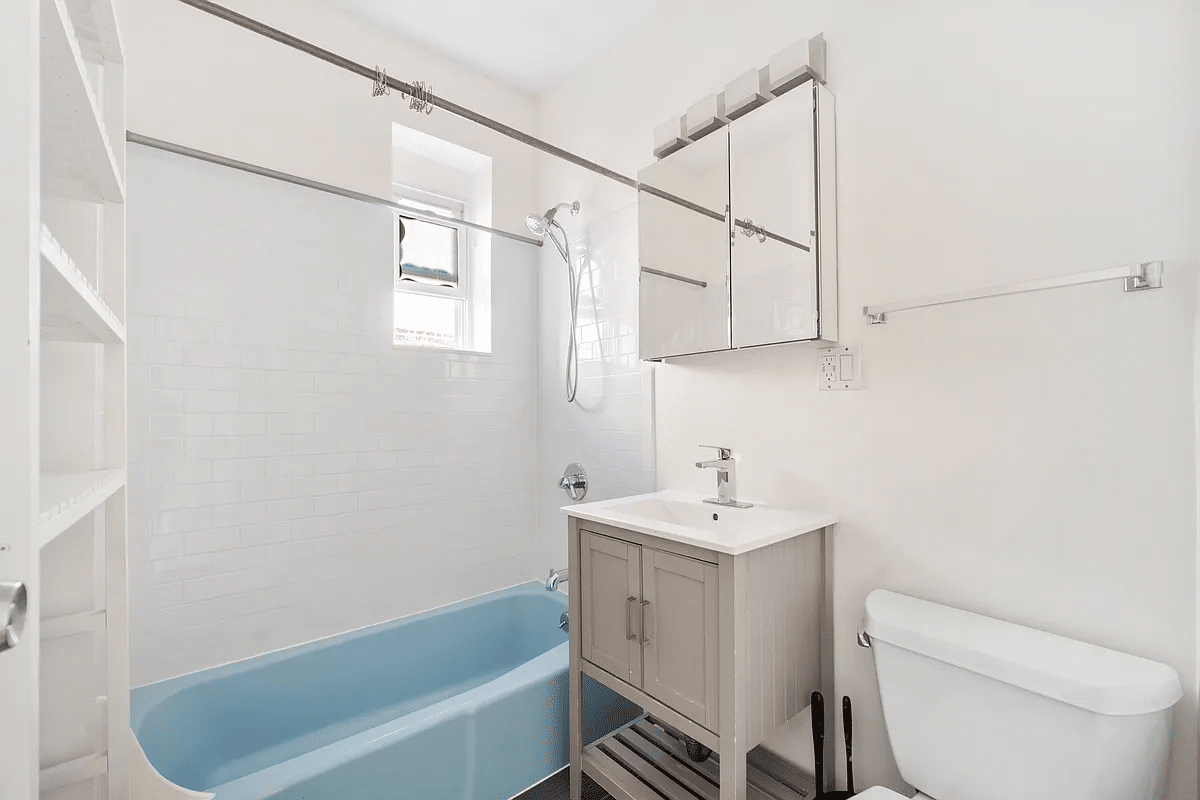 bathroom with blue tub, white toilet and tile