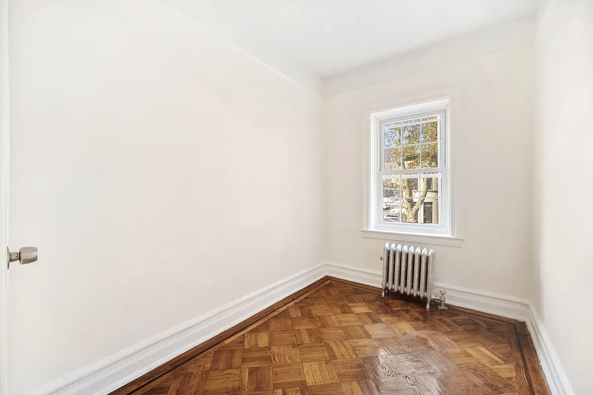 narrow bedroom with window, wood floor