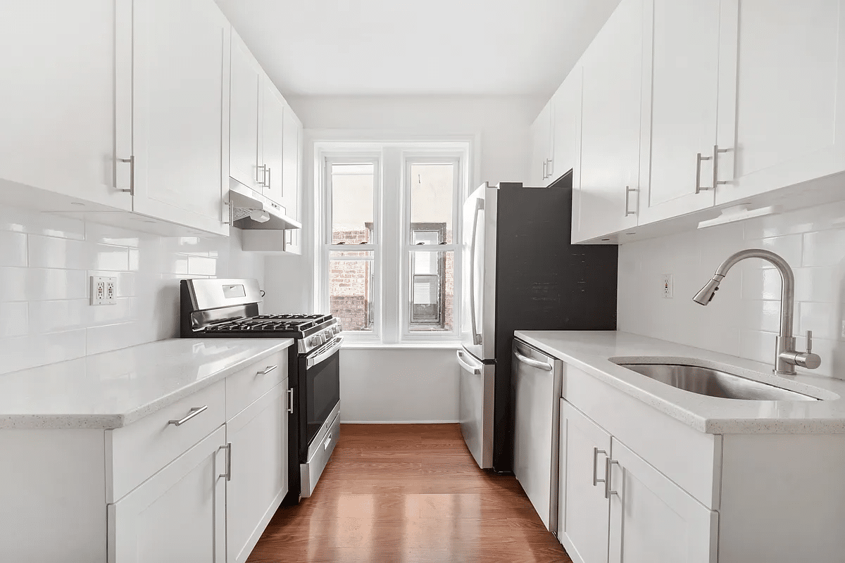 windowed kitchen with white cabinets and a dishwasher