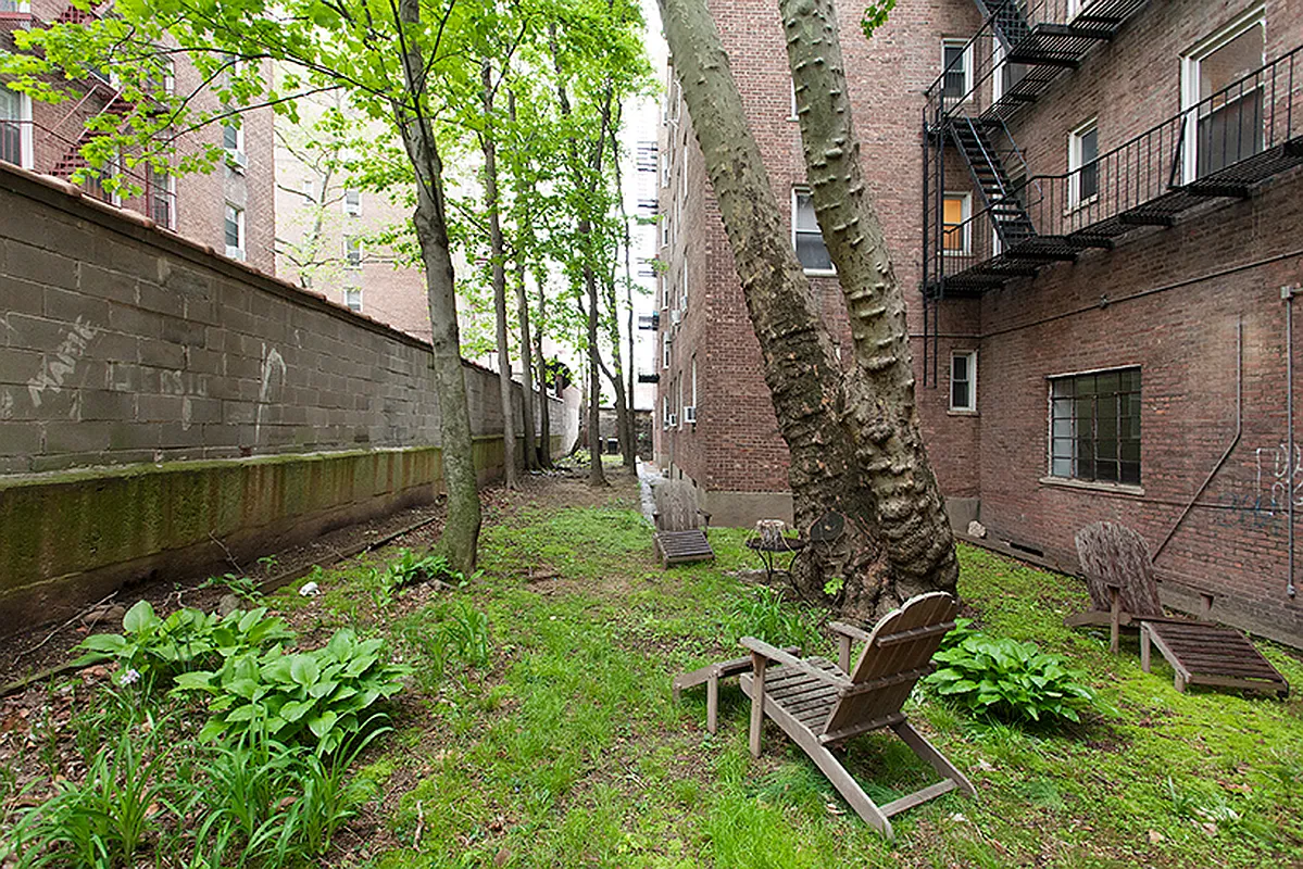 side yard with trees, hostas, grass and some seating