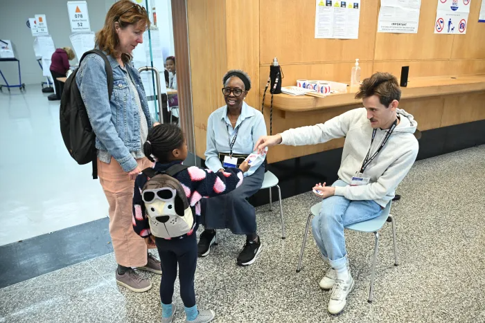 A poll worker at the Brooklyn Public Library’s Central Branch hands a future voter a sticker on Election Day.