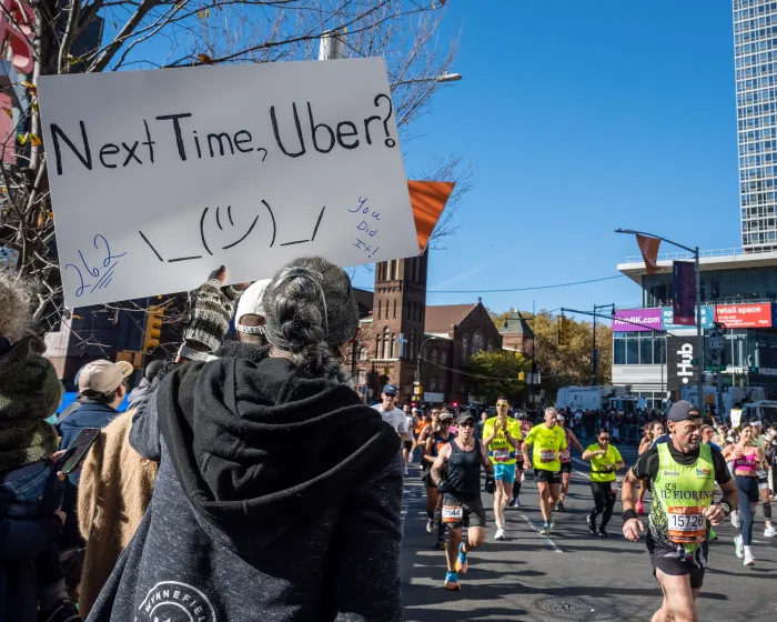 person holding a sign saying "next time, uber?"