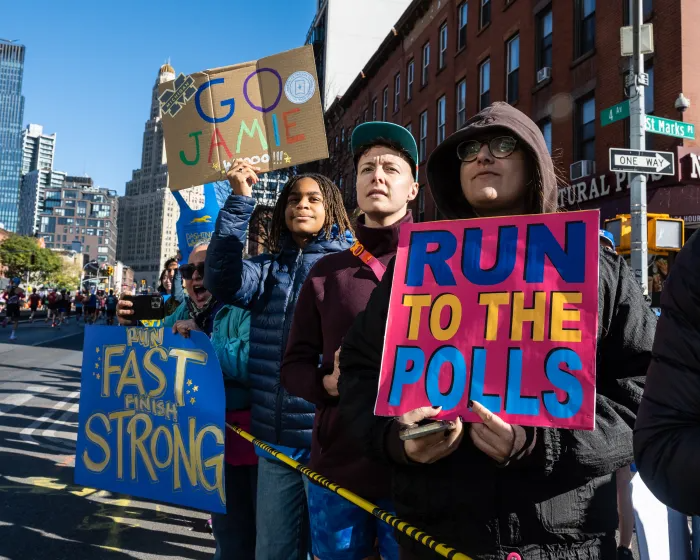 people with signs supporting runners and encouraging voting