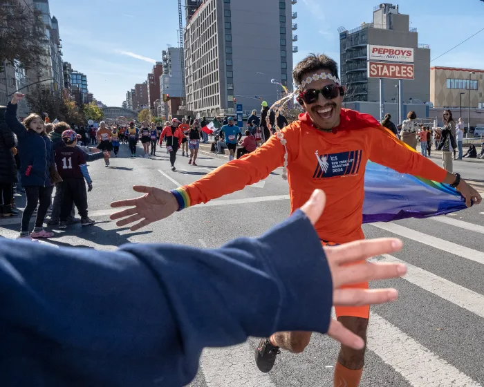 a runner in a cape reaches out to slap a hand