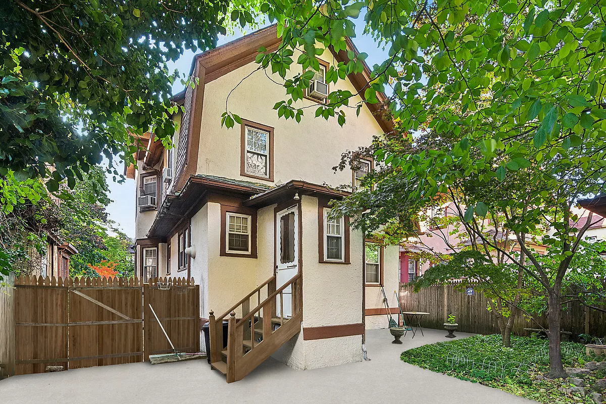 rear facade of the house with cream colored stucco and steps leading to a one-story mudroom extension