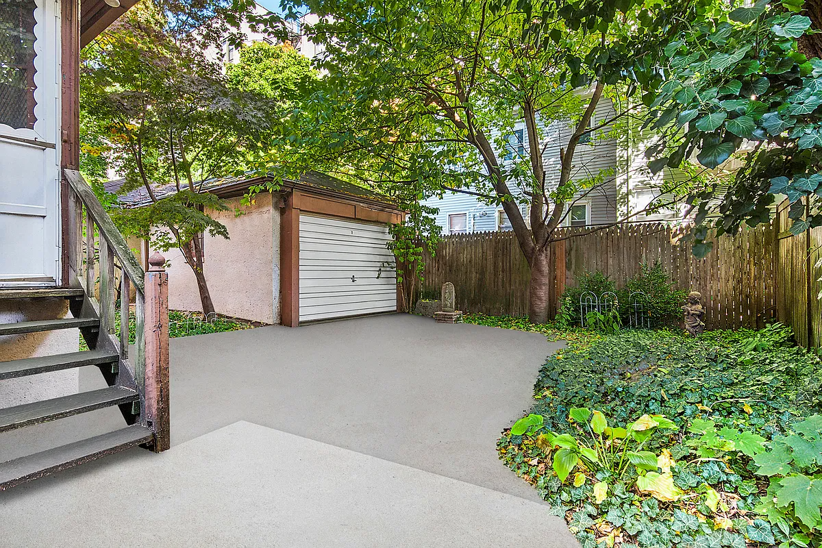 rear yard with paved patio, garage, and planting beds