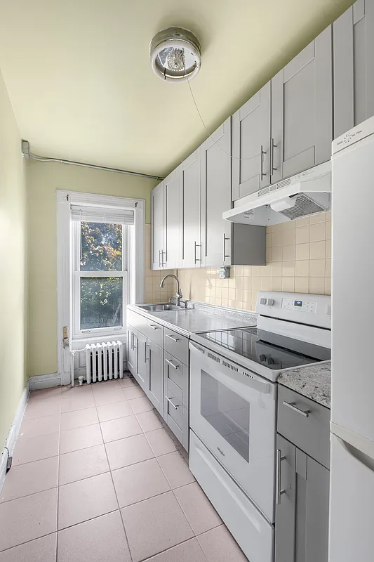 kitchen in rental apartment with gray cabinets, tile floor, white appliances