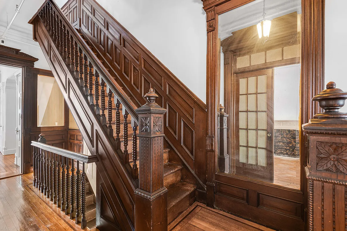 entry with original unpainted stair, wainscoting and a mirror