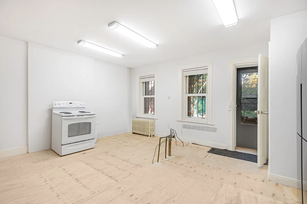 unfinished kitchen on garden level with plywood floor, a stove, and plumbing for a sink