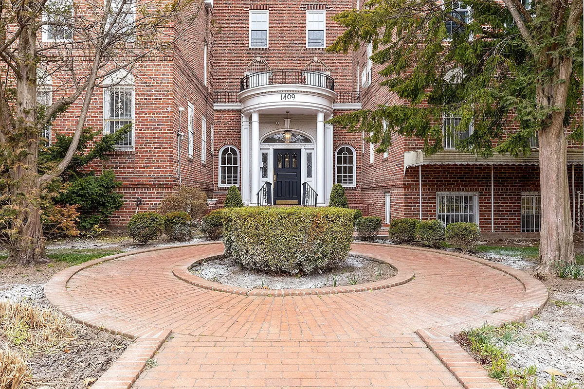 exterior of the red brick building with a brick walkway and a columned portico leading to a front door with fan light and sidelights